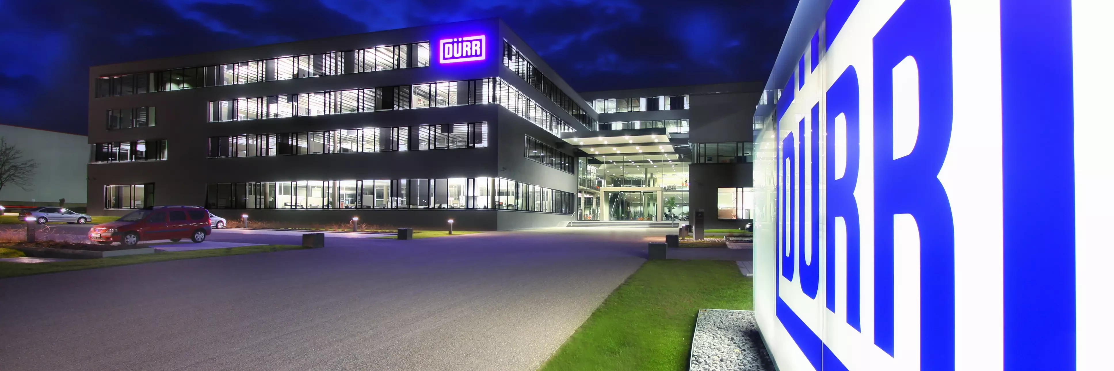 Dürr location headquarters in germany at night viewing the shining logo in the front of the building.